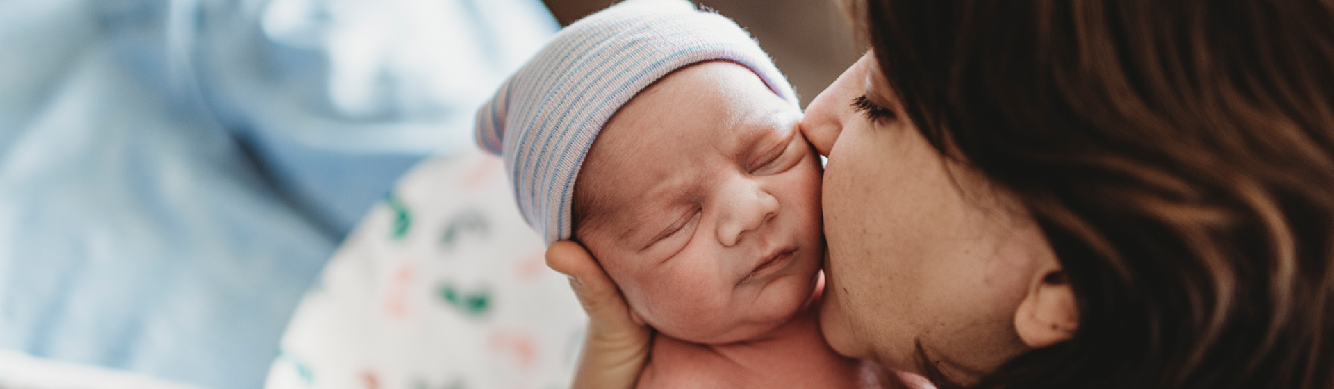Mother kisses newborn baby's cheek